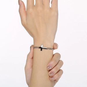 Close-up view of a minimalist silver stainless steel cross chain bracelet on wrist