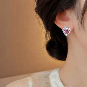 Macro detail of elegant pink cubic zirconia strawberry stud earring worn by a female model