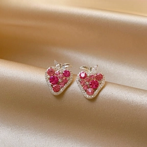 Detailed macro shot of pink zircon strawberry stud earrings on champagne gold satin background