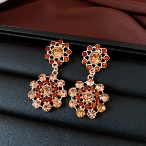 Close-up of vintage royal style gold hollow earrings with orange and champagne rhinestones