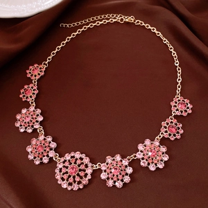 Close-up detail of a vintage gold necklace featuring pink rhinestone pendants