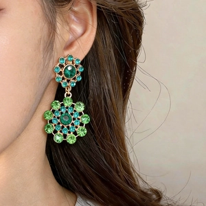 Macro view of vintage court style hollow earrings with green and teal rhinestones detail