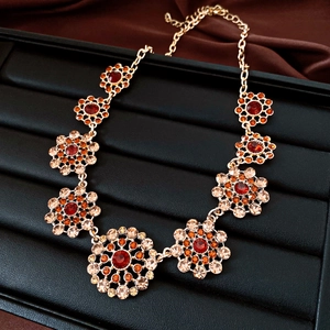 Detailed view of a vintage palace style necklace featuring red and orange crystals on gold