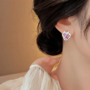 Detailed close-up shot of a fashionable pink zircon strawberry stud earring on a model's ear