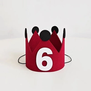 Detailed view of red felt birthday crown with number 6 and soft black pom-poms