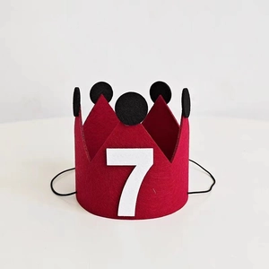 Detail of red felt crown birthday hat with white number seven and elastic strap