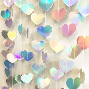 Iridescent heart garland hanging decoration for weddings and parties on beige background