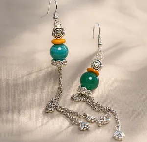 Pendientes de estilo étnico con cuentas verdes y detalles de largas borlas de metal plata