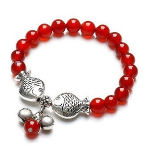 Detalle de pulsera de ágata roja con dijes de peces plateados y campanitas
