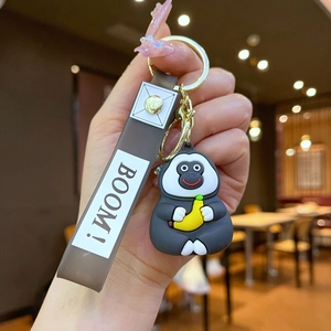 Detail of dark grey gorilla keychain with yellow banana and grey BOOM strap in hand