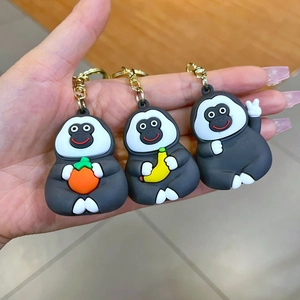 Detailed view of three cute PVC gorilla keychains with bananas and orange held in hand