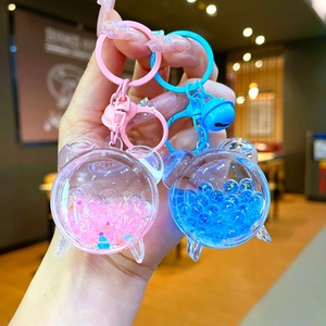 Handheld view of cartoon bear acrylic liquid sand keychains in pink and blue colors