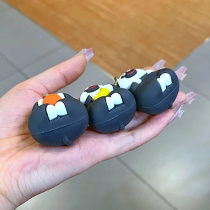Detailed view of three cute black monster keychains with white teeth in hand
