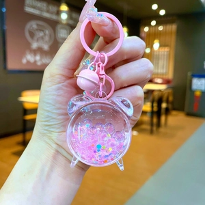 Detailed macro of a pink acrylic bear keychain with shimmering liquid glitter and a bell