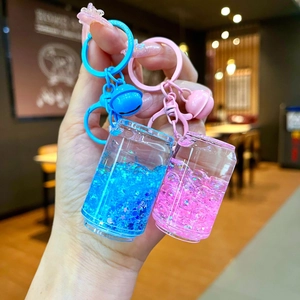 Handheld shot of creative luminous quicksand keychains in pink and blue soda can designs