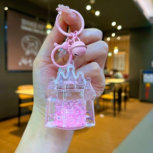 Detailed close-up of a pink castle-shaped liquid quicksand keychain held in a person's hand