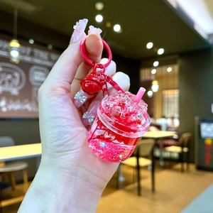 Close-up of bubble tea keychain with red liquid, glitter, and matching small bell