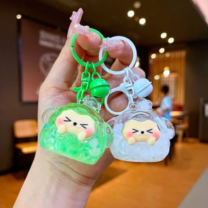 Handheld liquid glitter keychains with cartoon charms, bells and matte hooks in green and white