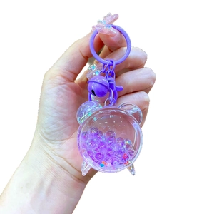 Cute purple acrylic liquid quicksand keychain with stars and bells in hand view