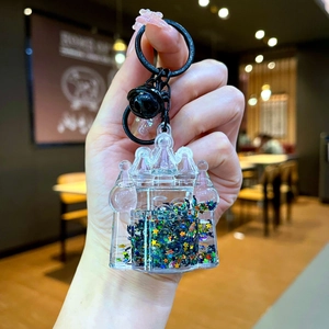Detail of castle-shaped liquid keychain with colorful star sequins and a black bell