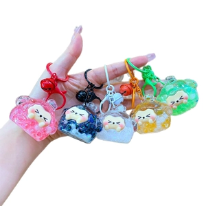 Five assorted mini cartoon bear liquid sand keychains with colorful bells and glitter