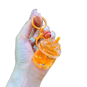 Luminous iceberg cup keychain with orange liquid sand and a red small bell charm