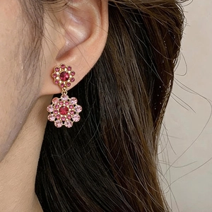 Close-up detail of vintage floral drop earrings with pink rhinestones worn on a model's ear