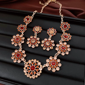 Close-up of vintage jewelry set with red and champagne crystals on floral motifs