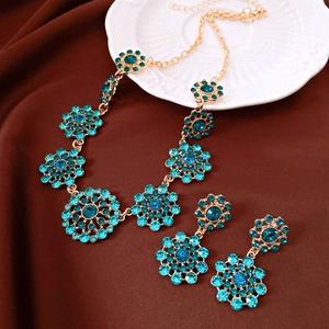 Close-up of vintage court style jewelry set with turquoise rhinestones on brown silk