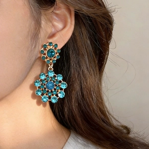 Close-up detail of vintage court style blue crystal gold drop earrings worn on a model's ear