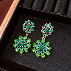 Detailed macro view of vintage green crystal hollow floral drop earrings in jewelry box