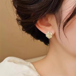 Détail de boucles d'oreilles fleurs ajourées avec pierres œil-de-chat sur un mannequin