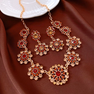 Vintage jewelry set with red rhinestones and gold floral patterns on brown satin background