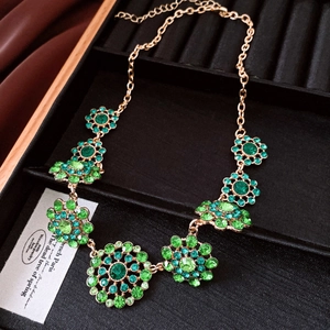 Detailed macro shot of vintage gold-toned necklace with green rhinestone floral circles