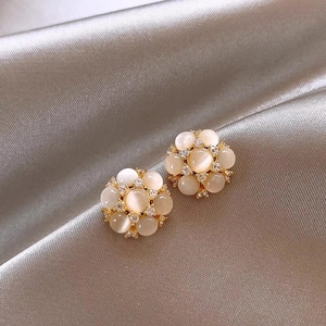 Détail rapproché de boucles d'oreilles fleurs avec pierres œil-de-chat et zircons brillants