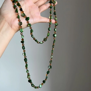 Detailed view of bohemian long necklace featuring green shell beads and brown crystals