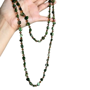 Long bohemian style necklace featuring green shell beads and brown faceted accents