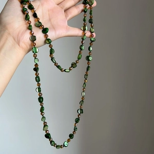 Detail showing long bohemian necklace with green shell beads and amber glass beads