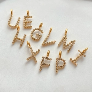 Dettaglio dei ciondoli a forma di lettera placcati in oro con zirconi brillanti