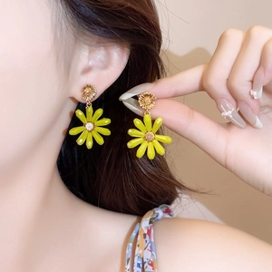 Macro detail of vibrant yellow daisy flower drop earrings worn by an Asian model