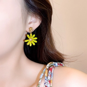 Detailed view of a vibrant yellow daisy stud earring being worn on a female model's ear
