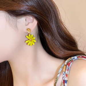 Detailed view of yellow daisy flower earrings on model for vacation style