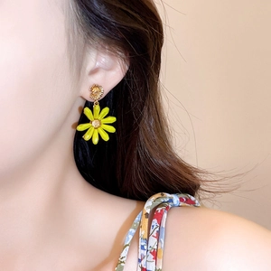 Close-up of vibrant yellow daisy flower earrings on model for vacation style