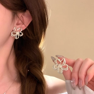 Macro shot of sweet minimalist hollow flower stud earring in silver finish worn on ear