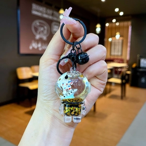 Detail of liquid sand astronaut keychain with gold stars inside a clear sphere