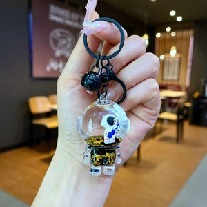 Detail of liquid sand keychain featuring a floating astronaut and golden star glitters