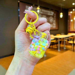 Close-up of creative liquid sand keychain with yellow beads, bell, and pink glitter butterfly