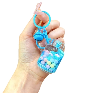 Luminous blue liquid quicksand keychain with macaron beads and bell on white background