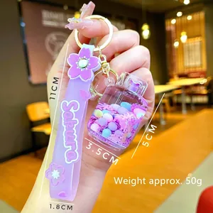 Handheld view of a Sakura-themed liquid oil keychain with purple strap and glitter bottle