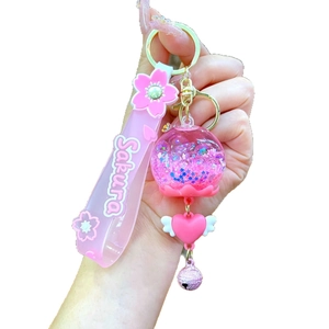 Pink Sakura luminous quicksand keychain with heart pendant and bell on white background